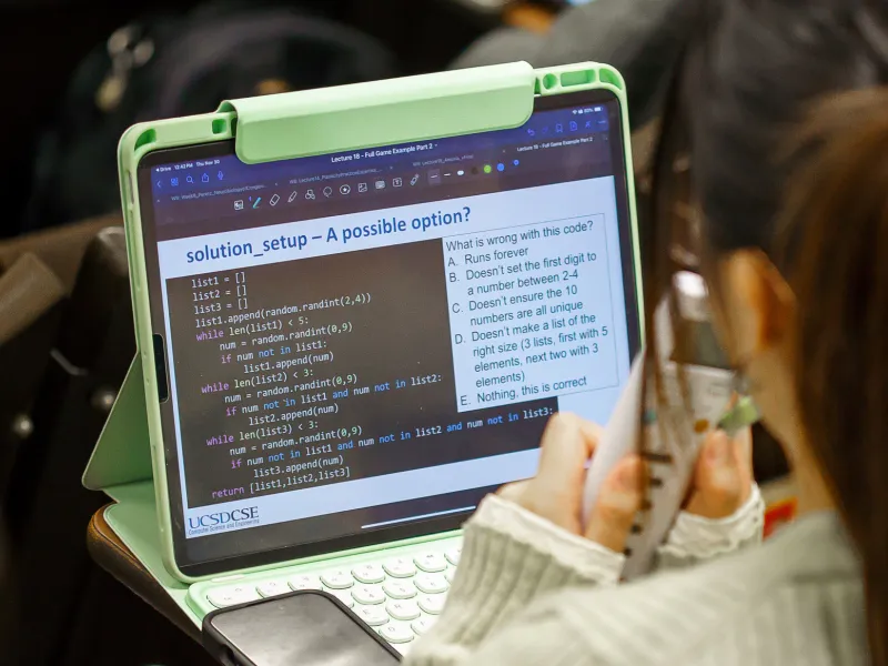 Student looking at their laptop.  The laptop shows a question to them about GenAI produced code.  Image Credit: Credit is David Baillot from UC San Diego Jacobs School of Engineering